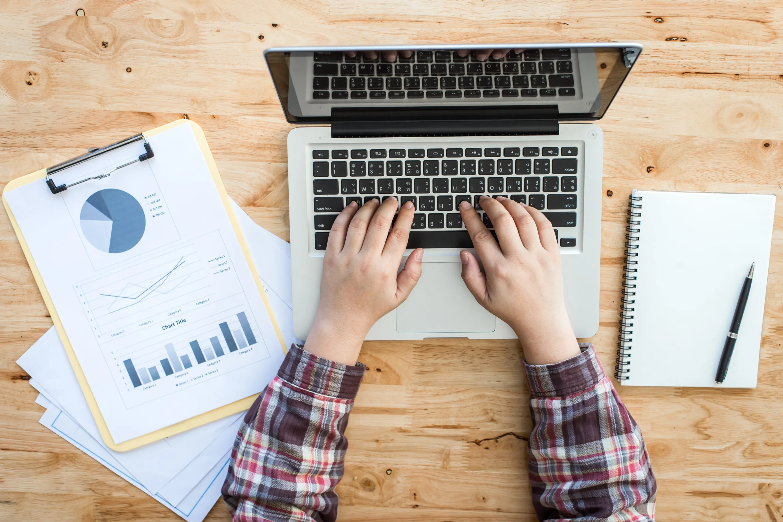 A working wooden desk(table) with notebook computer, coffee cup, paper, pencil and hand
